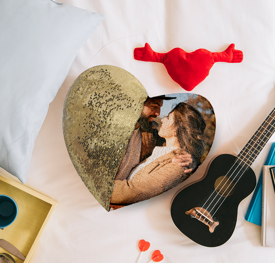 Qstomize.com - Create Memories: Heart-Shaped Custom Sequin Pillow Romantic pillow arrangement with heart-shaped decor, cozy beverage, and whimsical ukulele for couples.